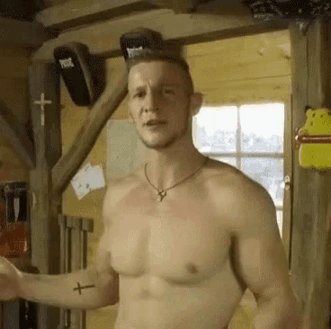 a shirtless man has a cross tattoo on his arm .