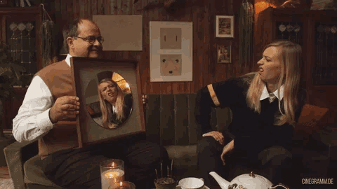 a man is holding a framed picture of a woman while a woman sits on a couch