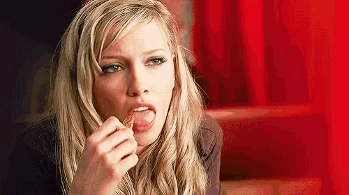 a woman is sticking her tongue out while eating a snack .