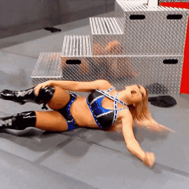 a woman in a blue and black outfit is laying on the floor with her arms outstretched