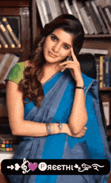 a woman in a blue saree is standing in front of a book shelf