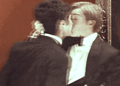 two men in tuxedos kissing each other on the cheek
