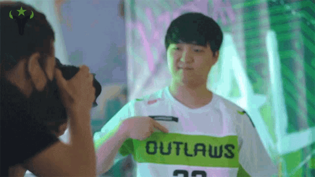 a man taking a picture of another man wearing a outlaws shirt