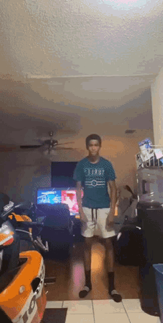 a man standing in a living room wearing a t-shirt that says ' shark ' on it