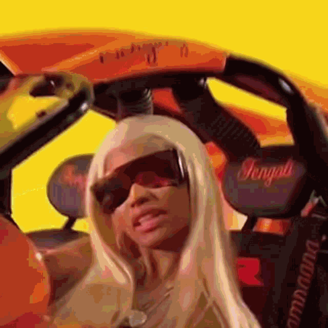a woman is sitting in a car wearing sunglasses and a necklace .