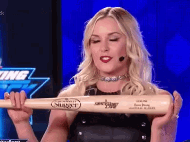 a woman is holding a slugger baseball bat in her hands