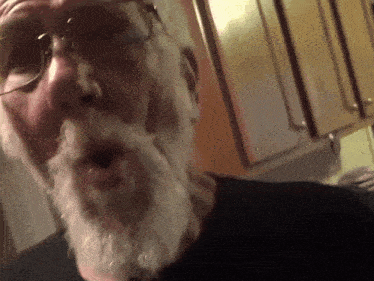 a man with glasses and a white beard looks at the camera