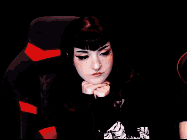 a woman with a piercing in her nose is sitting in a black chair