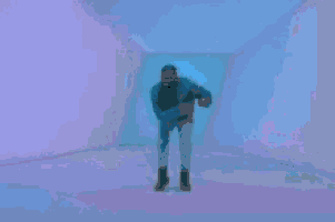 a man is standing in a room with a blue light behind him .