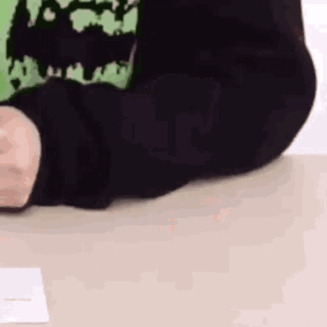 a person in a black sweater is sitting at a table with a piece of paper in front of them .