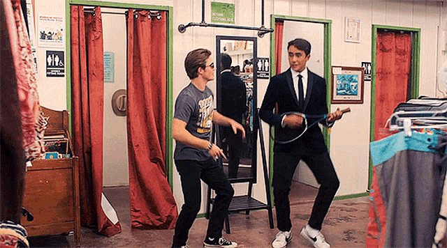 two men are dancing in a dressing room with a sign above them that says smoking is prohibited