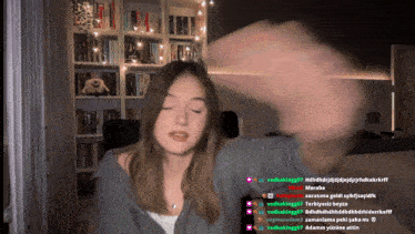 a woman 's face is visible in front of a bookshelf and a bunch of people are talking to her