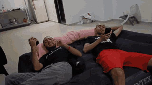 two men are laying on a couch that says intex on it