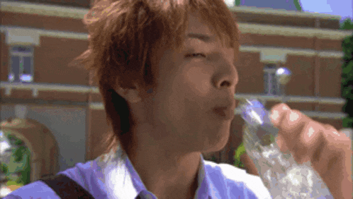 a man drinking water from a clear bottle with ice cubes
