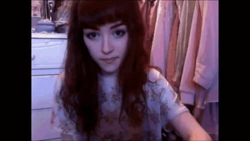 a girl with long red hair is standing in front of a closet