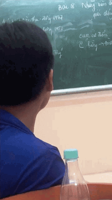 a man sits in front of a blackboard that says bac b8 on it
