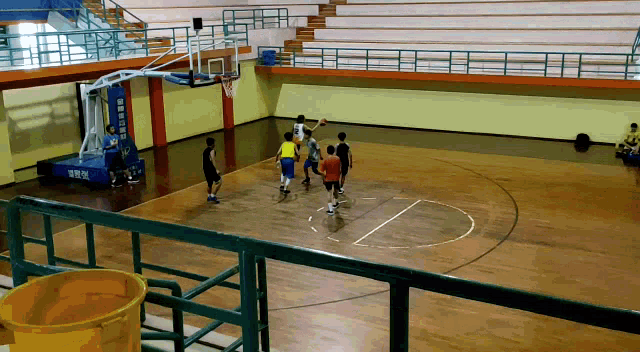 a group of people are playing basketball on a court with a bucket in front of them that says ' basketball ' on it