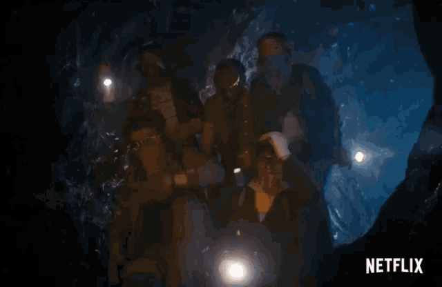 a group of people walking through a cave with a netflix logo in the corner