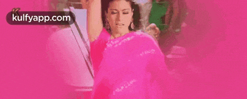 a woman in a pink saree is dancing with her arms in the air on a pink background .