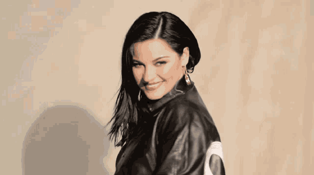 a woman wearing a black leather jacket with a white letter o on the back
