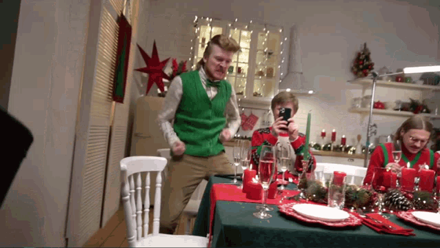 a man in a green vest is dancing at a table
