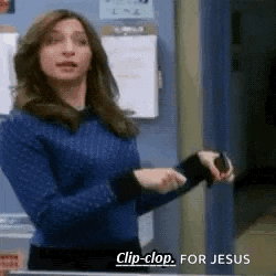 a woman in a blue sweater is standing in a room and holding a cell phone .