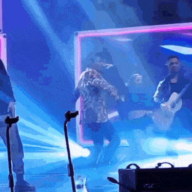 a group of people are standing on a stage playing instruments and singing into microphones .