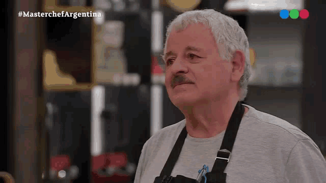 a man with gray hair and a mustache is standing in front of a screen that says masterchef argentina