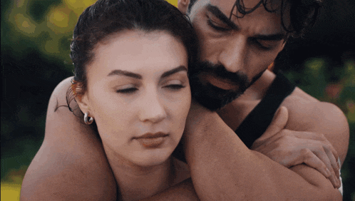 a man with a beard is hugging a woman in a black tank top