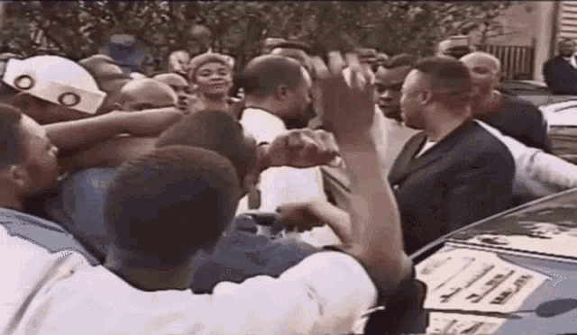 a crowd of people are gathered around a car with a sign on the hood that says ' a ' on it .