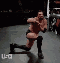 a man in a wrestling ring is doing a kneeling squat .