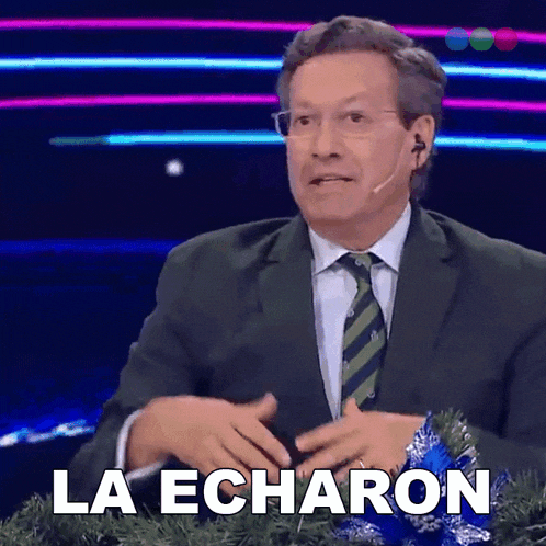 a man in a suit and tie says " la echaron " in front of a christmas tree