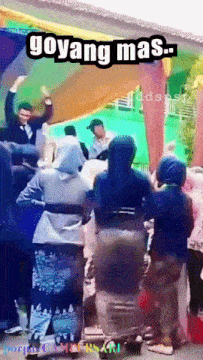a group of people are dancing in front of a sign that reads goyang mas