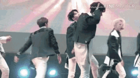 a group of men are dancing on a stage in front of a microphone .