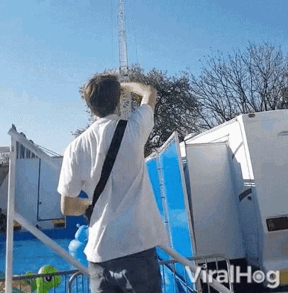 a man in a white shirt is standing in front of a blue wall and a white van .
