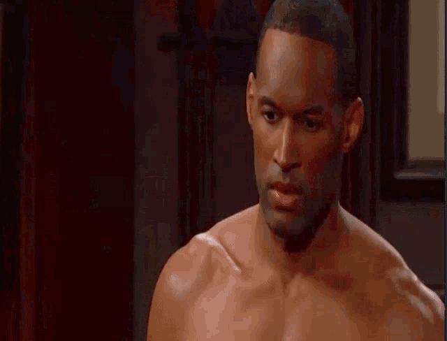 a shirtless man is looking at the camera with a serious look on his face .