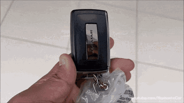 a person is holding a jaguar car key fob in their hand