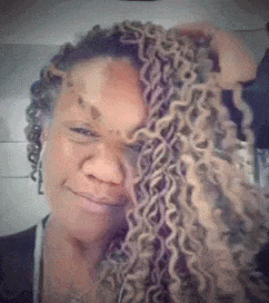 a woman with dreadlocks is smiling and looking at the camera .