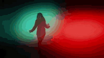 a woman is dancing in a dark room with red and green lights .