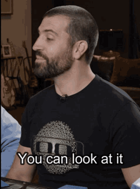 a man with a beard wearing a black shirt that says " you can look at it "