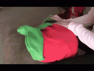 a person is holding a red apple shaped pillow