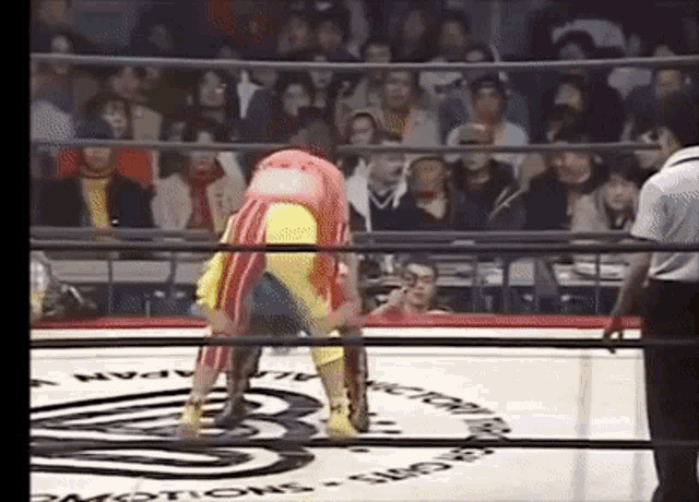 two women are wrestling in a ring with a referee in the background .
