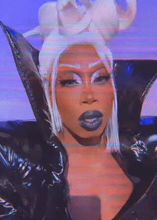 a close up of a drag queen wearing a black jacket and a wig .
