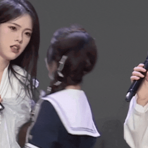 a woman in a sailor suit is holding a microphone while another woman looks on .