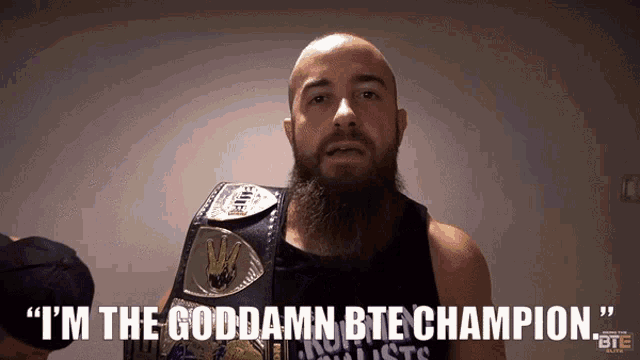 a bald man with a beard is wearing a bte championship belt