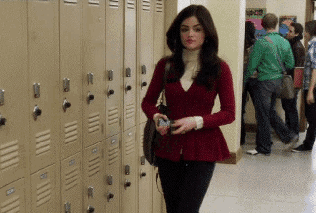 a woman in a red sweater is standing in front of a row of lockers with the numbers 1 through 12 on them