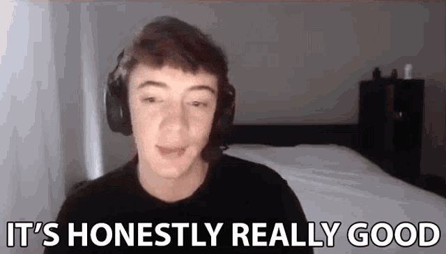 a young man wearing headphones says `` it 's honestly really good '' while sitting in front of a bed .