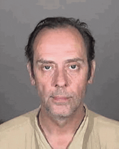 a man with a beard is wearing a tan shirt and a necklace .