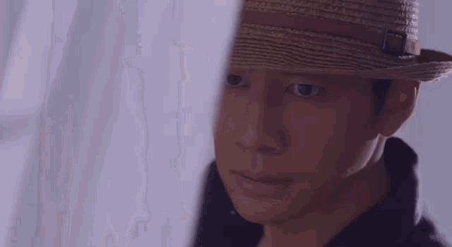 a man in a suit and hat is standing in front of a window looking out .