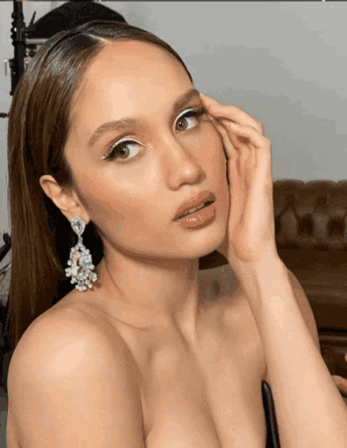 a woman without a shirt is wearing a pair of earrings